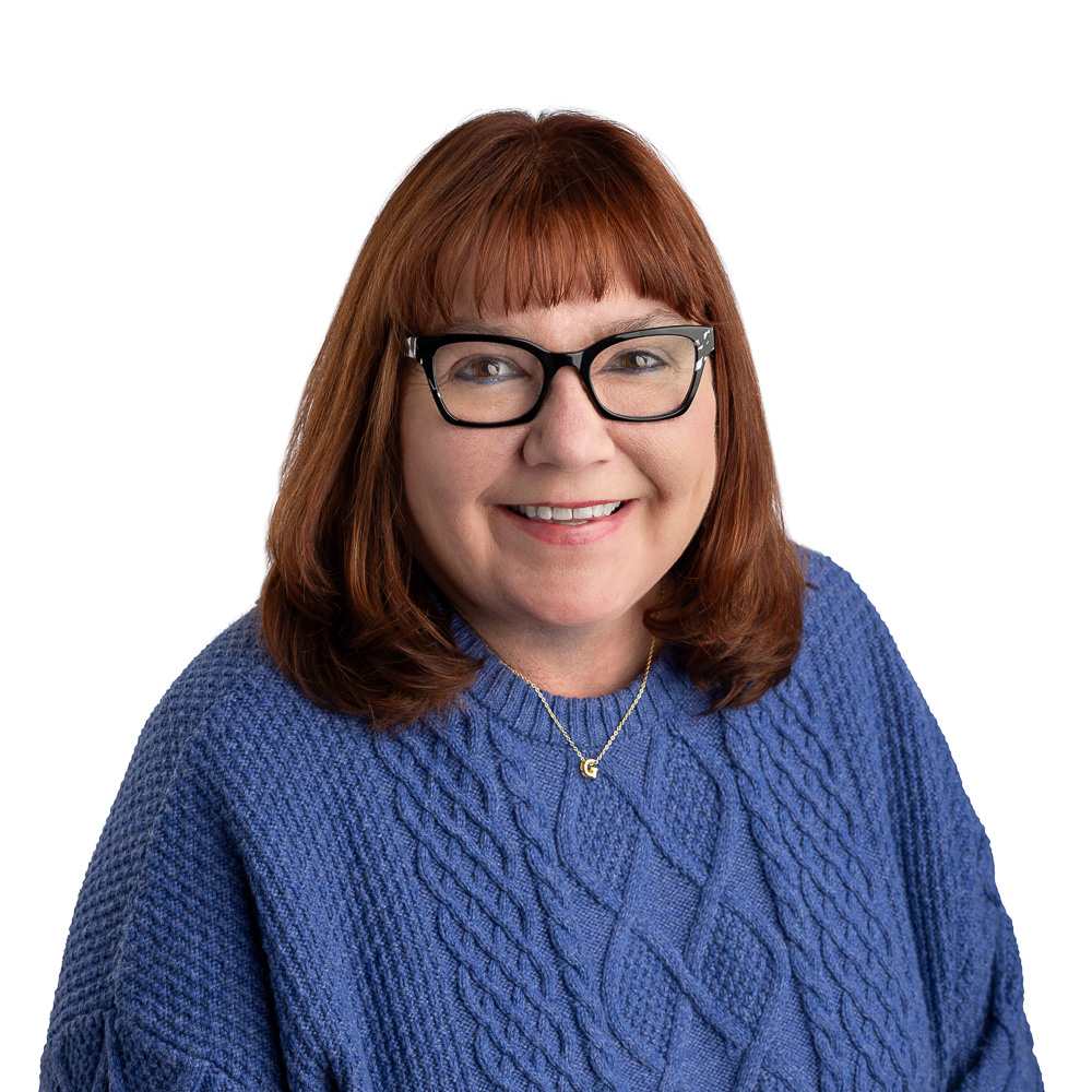 Middle aged woman, brown hair, dark framed glasses, smiling